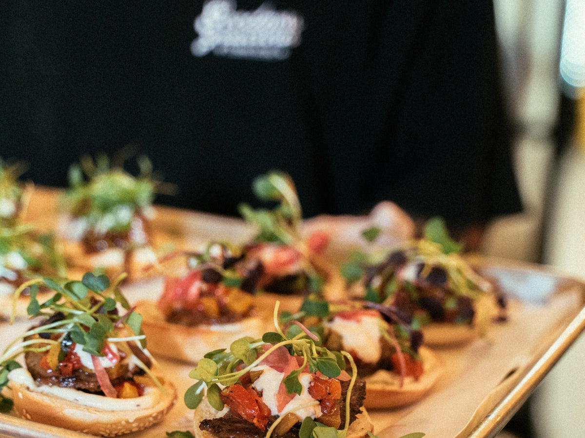 A Goodness Gracious staff member carrying a tray of bagel canapés at an event